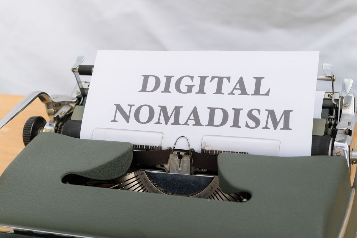 a close up of a typewriter with a paper that reads digital nomadism