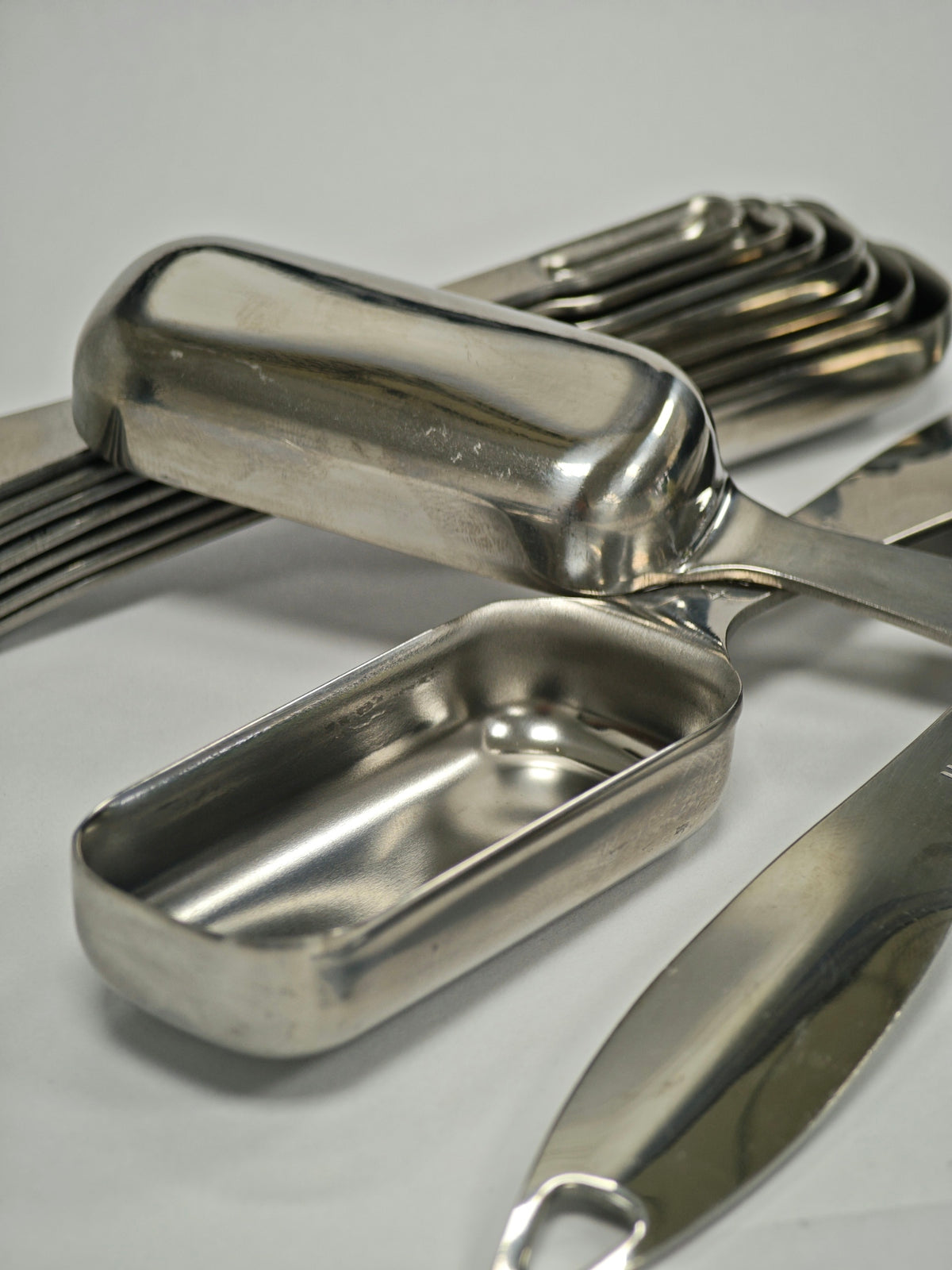 Stainless steel scoops and measuring spoons on a white surface.